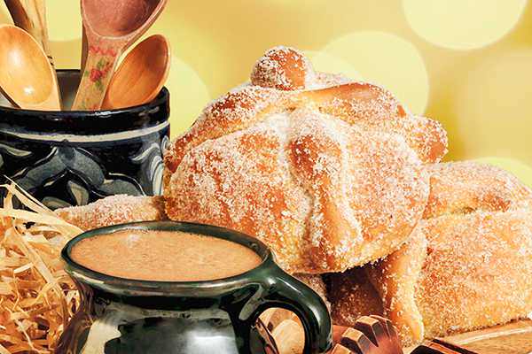 A cup of hot chocolate and a round loaf of sugared bread (pan de muerto)