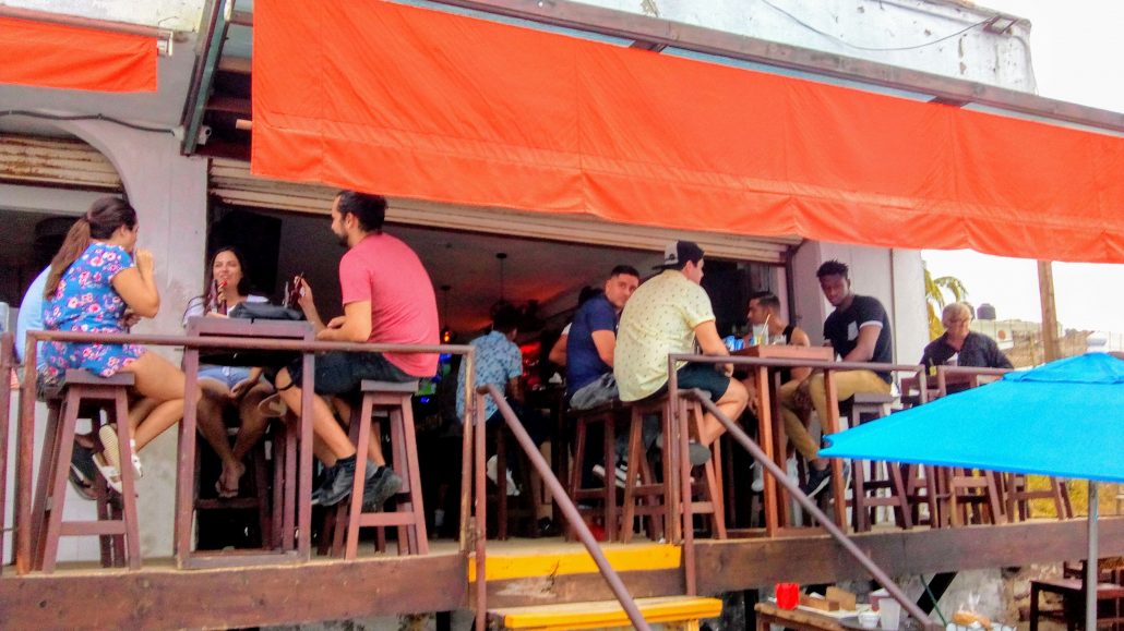 People seated around tables on the deck of el solar bar