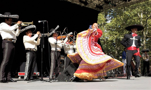 Mariachi musicians performing with a folkloric dancer on stage.