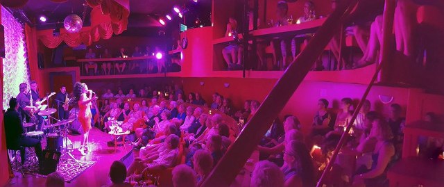 A singer performs on stage, in front of a live audience, in a small theater in Puerto Vallarta.