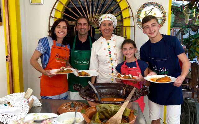 A family poses with chef Rosie, with the plates they prepared in her cooking class in Puerto Vallarta.