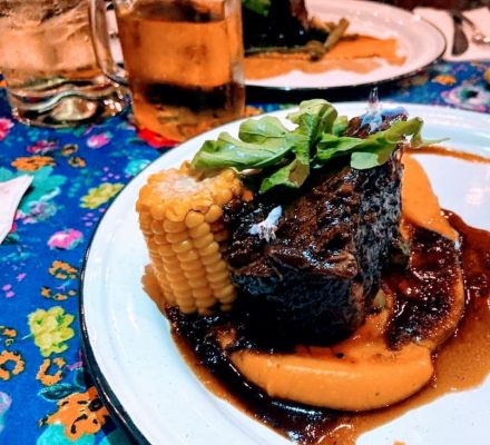 a plate with short rib and corn on the cob.