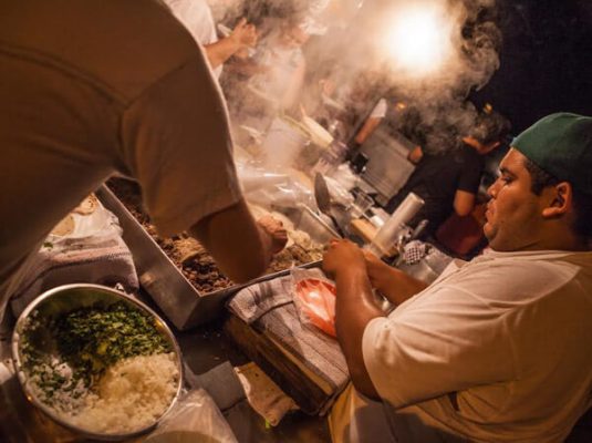 A cook prepares a taco, at a street stand,  at night in Puerto Vallarta. 