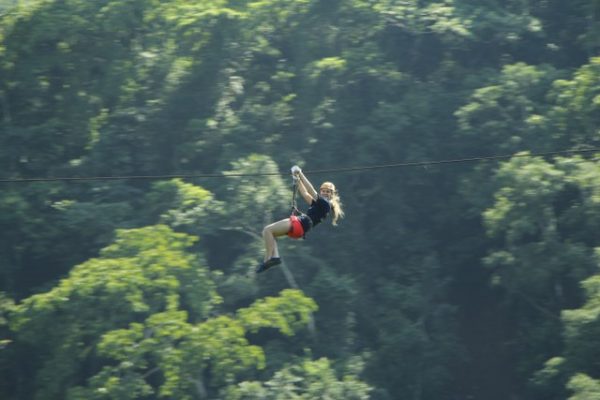 a young girl flying through the jungle on a zip line in Puerto Vallarta Mexico.