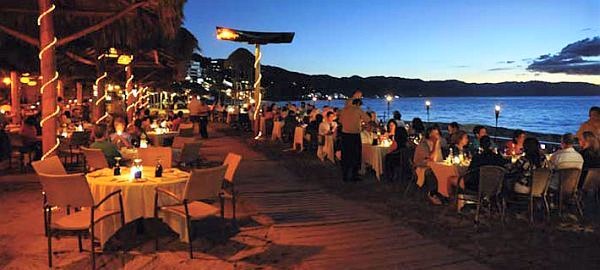 diners gathered around candle lit tables on Los Muertos Beach at La Palapa Restaurant in Puerto Vallarta