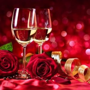 two glasses of white wine with red roses infront