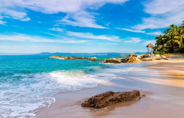 a beach in puerto vallarta with blue ocean, blue sky, and scattered clouds