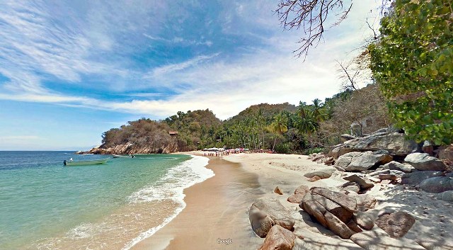 a bay and beach in Puerto Vallarta with a small boat anchored off shore. 