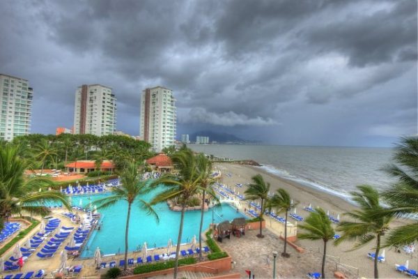 Ominous dark clouds over a hotel pool and beach in Puerto Vallarta.